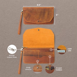 May include: A brown leather wallet with a snap closure, 8 card holders, a cash slot, and a strong metal hook. The wallet measures 8.5 inches by 5 inches.