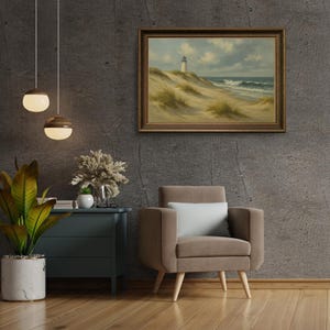 May include: A framed landscape painting depicts a lighthouse on a sandy dune overlooking the ocean. The artwork is in a dark wooden frame and hangs on a textured gray wall. A brown armchair with a white pillow sits below the painting.