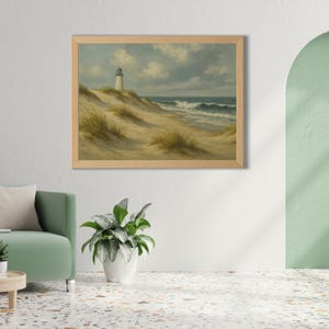 May include: A framed landscape painting depicts a coastal scene. A white lighthouse stands atop a sandy dune, with ocean waves crashing in the distance. The sky is cloudy, and the painting has a vintage aesthetic.