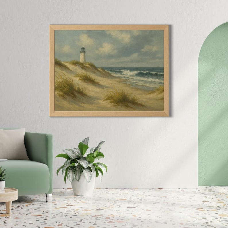 May include: A framed landscape painting depicts a coastal scene. A white lighthouse stands atop a sandy dune, with ocean waves crashing in the distance. The sky is cloudy, and the painting has a vintage aesthetic.
