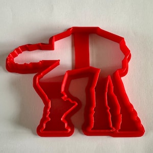 May include: Red plastic cookie cutter shaped like an AT-AT walker from Star Wars.