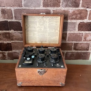 Peut inclure: Une boîte en bois vintage contenant un ensemble de test électrique noir avec plusieurs boutons et un cadran. La boîte a un couvercle à charnières avec des instructions pour utiliser l'ensemble de test Leeds & Northrup No. 432-A imprimées à l'intérieur.