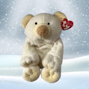 Può includere: Un peluche a forma di orso polare con corpo color crema, orecchie beige e naso marrone. L'orso ha occhi neri e un'etichetta rossa a forma di cuore con la scritta "RUFFLES". Il giocattolo è ambientato su uno sfondo innevato.