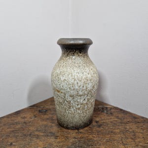 May include: A small, brown and white ceramic vase with a speckled glaze.