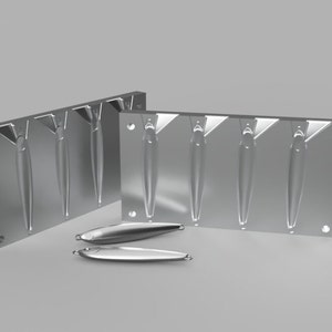 May include: Two metal molds for casting fishing lures. The molds are made of aluminum and have a silver finish. Each mold has four cavities for casting lures. The molds are shown with two finished lures.
