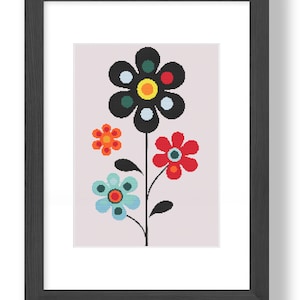 Puede incluir: Una impresión enmarcada de una flor estilizada con pétalos negros, rojos, azules, verdes, naranjas y amarillos. La flor está sobre un fondo rosa claro.