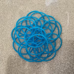 May include: A pile of bright blue rubber bands, arranged in a circular pattern.