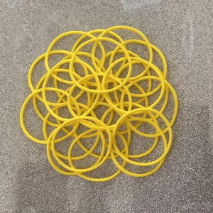 May include: A pile of yellow rubber bands, arranged in a circular pattern.