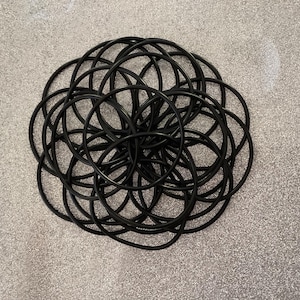 May include: A close-up of a stack of black rubber o-rings arranged in a circular pattern.