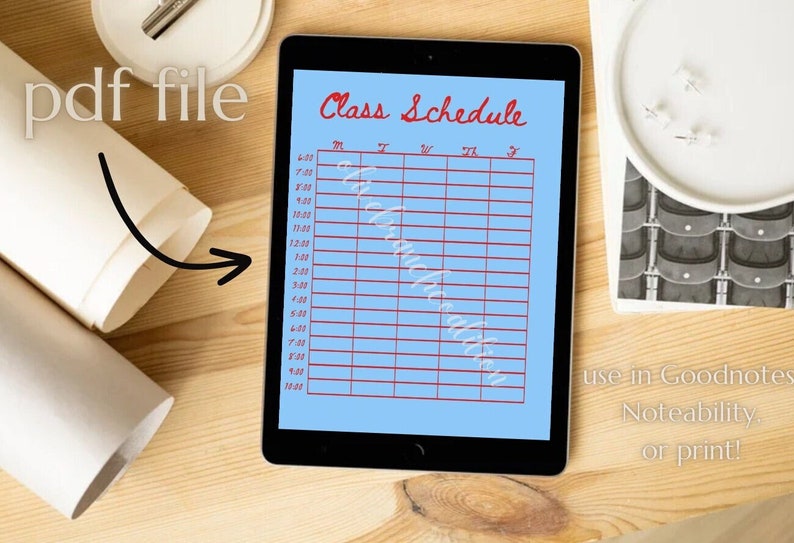May include: A blue digital planner with a red "Class Schedule" title and a grid for scheduling classes. The planner is on a wooden surface with a white plate and a roll of paper.