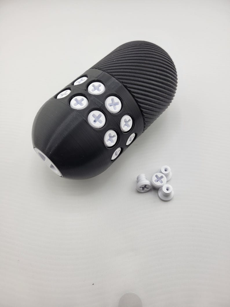 May include: A black, cylindrical object with a ridged top and a rounded bottom. The object has several white, cross-shaped accents. Several loose white accents are also present.