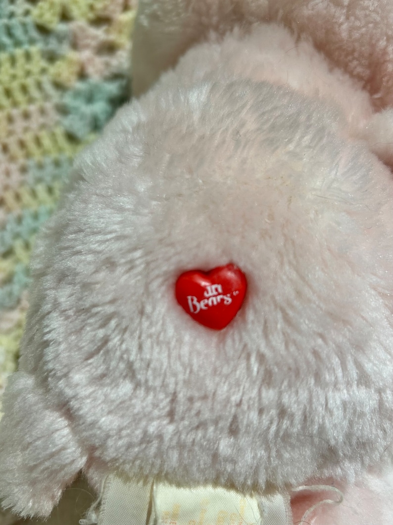 Puede incluir: Oso de peluche rosa con un coraz&oacute;n rojo en el pecho que dice "Care Bears" en letras blancas.
