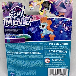 Puede incluir: Una figura de My Little Pony: La Pel&iacute;cula de color azul y naranja con cola de sirena. La figura est&aacute; empaquetada en una caja colorida con una etiqueta de advertencia que dice "MISE EN GARDE: RISQUE D'&Eacute;TOUFFEMENT-Petites pi&egrave;ces. D&eacute;conseill&eacute; aux enfants de moins de 3 ans."
