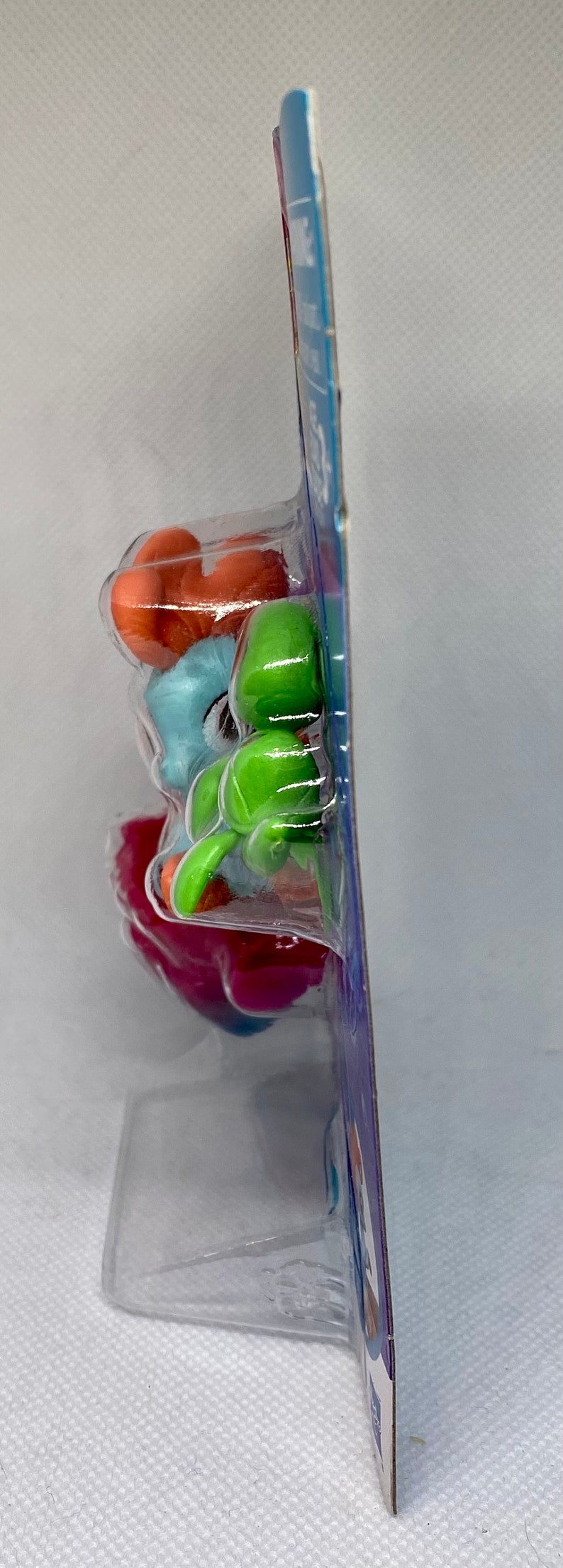 Puede incluir: Una bl&iacute;ster de pl&aacute;stico que contiene cuatro peque&ntilde;as figuras de pl&aacute;stico. Las figuras son de varios colores, incluyendo naranja, azul, verde y rosa. Las figuras est&aacute;n apiladas, con la figura naranja en la parte superior.