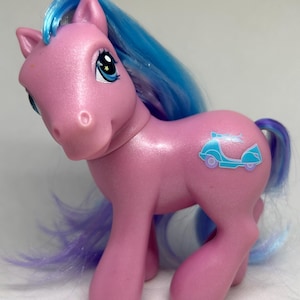 Può includere: Pony My Little Pony rosa con crinoline blu e viola. Il pony ha un simbolo di scooter blu e bianco sul fianco.