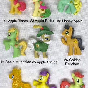 Puede incluir: Nueve figuras de juguete de ponis coloridos. Cada poni tiene un diseño y un nombre únicos, incluyendo Apple Bloom, Apple Fritter, Honey Apple, Apple Munchies, Apple Strudel, Golden Delicious, Golden Grape, Lavender Fritter y Peachy Sweet.