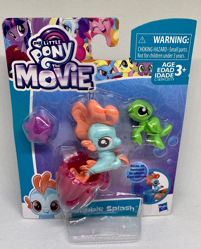 Puede incluir: Set de juguetes My Little Pony La Pel&iacute;cula Bubble Splash con un personaje de caballito de mar azul y naranja con una concha rosa y un personaje de tortuga verde. Los personajes tienen ventosas en sus pies. El empaque incluye el texto "Sticks on Ventouse Se adhiere Com ventosa" y "Bubble Splash".