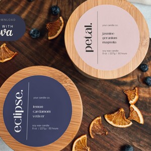 Zoom in on the top of two candle lids. Left candle lid has a navy blue label with white details. Right candle has a rose pink label with black detailing. Both have a minimalistic candle name written at 90 degrees along the left side of the candle.