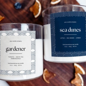 Two candles with custom labels. Left label is beige, right label is navy blue. Both have line art drawing around the edges framing text in the middle. There are custom text fields for the candle company, name, scents, and size.