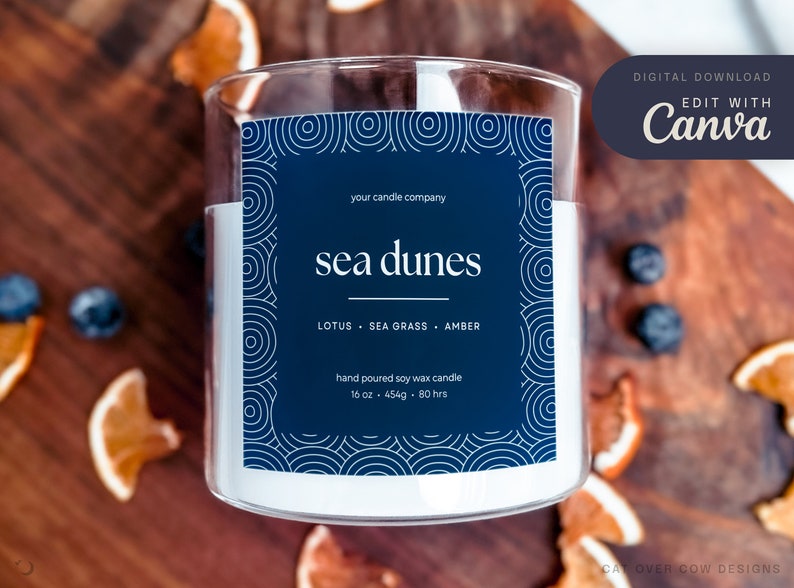 Single glass candle on top of a cozy rustic background. Digital download edit with canva. Candle label has illustrated border that looks like tidal waves shibori pattern. Candle named sea dunes with editable company name, scents, size, and other info