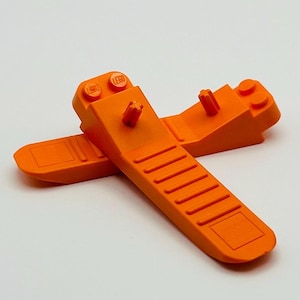May include: Two orange LEGO pieces with the word "LEGO" printed on them. The pieces are designed to be used as a ramp or slope for building.