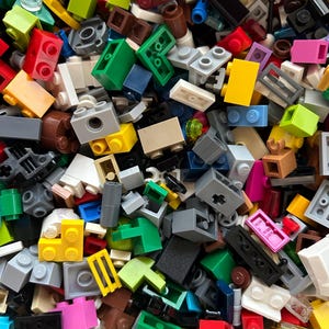 Peut inclure: Une grande collection de briques Lego color&eacute;es de diff&eacute;rentes formes et tailles. Les briques sont en plastique et sont de diff&eacute;rentes couleurs, notamment rouge, bleu, vert, jaune et noir.
