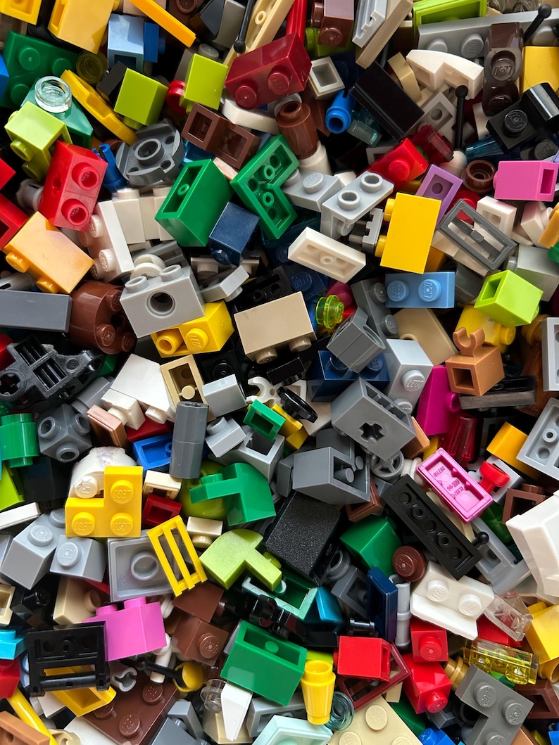 Peut inclure: Une grande collection de briques Lego color&eacute;es de diff&eacute;rentes formes et tailles. Les briques sont en plastique et sont de diff&eacute;rentes couleurs, notamment rouge, bleu, vert, jaune et noir.