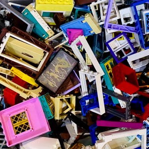 Puede incluir: Un surtido desordenado de bloques de construcción de plástico de colores. Los bloques son de varias formas y tamaños, incluyendo ladrillos rectangulares, marcos de ventanas y paneles decorativos. Los colores incluyen amarillo, azul, rosa, blanco y rojo. Un panel con un diseño de dragón dorado es visible.