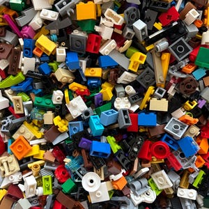 Peut inclure: Une grande collection de briques Lego color&eacute;es de diff&eacute;rentes formes et tailles. Les briques sont en plastique et sont de diff&eacute;rentes couleurs, notamment rouge, bleu, vert, jaune et noir.