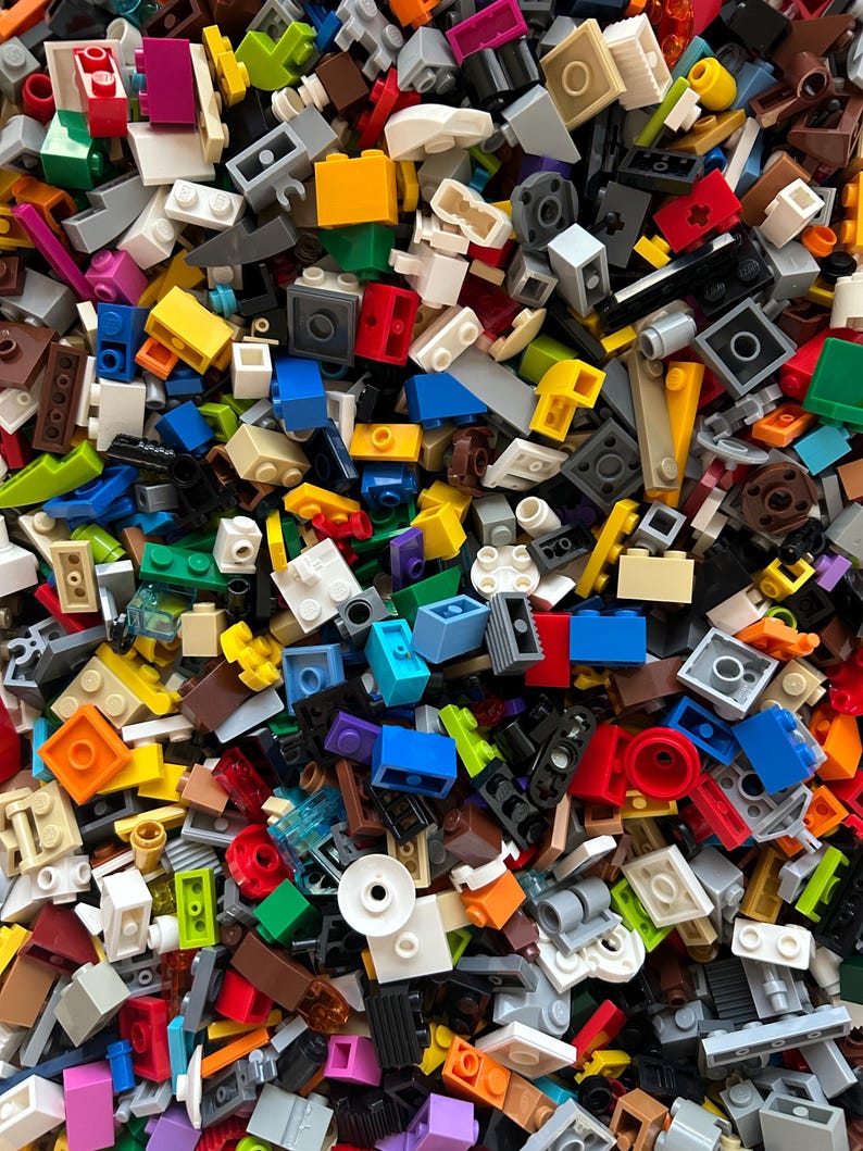 Peut inclure: Une grande collection de briques Lego color&eacute;es de diff&eacute;rentes formes et tailles. Les briques sont en plastique et sont de diff&eacute;rentes couleurs, notamment rouge, bleu, vert, jaune et noir.