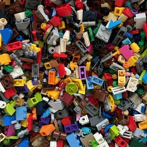 Peut inclure: Une grande collection de briques Lego color&eacute;es de diff&eacute;rentes formes et tailles. Les briques sont un m&eacute;lange de couleurs primaires, notamment le rouge, le bleu, le jaune, le vert et l'orange. Il y a aussi quelques briques noires, blanches et brunes. Les briques sont toutes dans un ordre al&eacute;atoire, cr&eacute;ant un motif color&eacute; et chaotique.