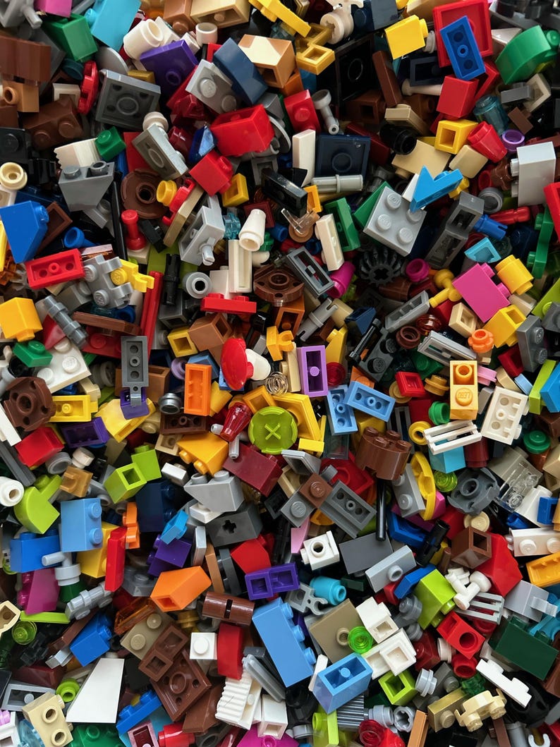 Peut inclure: Une grande collection de briques Lego color&eacute;es de diff&eacute;rentes formes et tailles. Les briques sont un m&eacute;lange de couleurs primaires, notamment le rouge, le bleu, le jaune, le vert et l'orange. Il y a aussi quelques briques noires, blanches et brunes. Les briques sont toutes dans un ordre al&eacute;atoire, cr&eacute;ant un motif color&eacute; et chaotique.