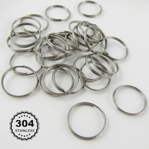 May include: A pile of silver key rings made of 304 stainless steel. The key rings are all the same size and are arranged in a random pattern.