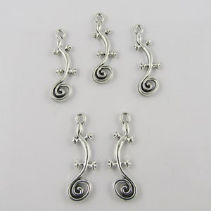 May include: Five silver-toned lizard charm pendants with a curled tail design. The charms are approximately 5 cm long.