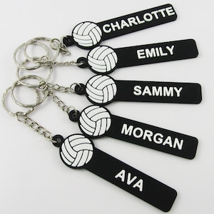 May include: Five black rectangular keychains with white volleyball graphics and the names Charlotte, Emily, Sammy, Morgan, and Ava printed in white. Each keychain features a silver metal split ring attached by a short silver metal chain.