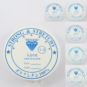 May include: A white spool of strong and stretchy elastic cord with a blue diamond logo and the text "Strong & Stretchy" and "Crystaline" printed on it. The spool is labelled with the size "1.0" and the text "Water-soluble" in Japanese.