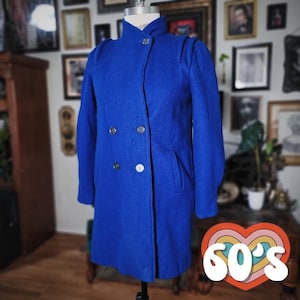 May include: A vibrant blue vintage coat with a double-breasted design. The coat features a high collar, shoulder detailing, and silver buttons. The coat is displayed on a mannequin. A retro graphic with the text "60's" is in the foreground.