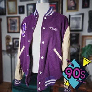 May include: Purple vintage letterman jacket with cream-colored sleeves and white accents. Features the name "Trisha" embroidered on the chest and a large "RS" patch. A classic 90s style jacket.