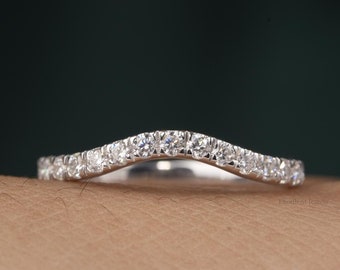 May include: A delicate, curved wedding band with a row of small, sparkling diamonds.