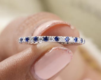 May include: A delicate eternity band with alternating blue sapphires and white diamonds set in a silver band.