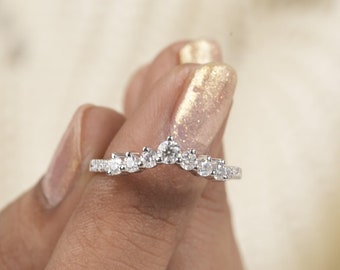 May include: A delicate, curved wedding band with a row of sparkling diamonds set in a white gold band.