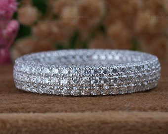 May include: A silver band ring with multiple rows of small, clear cubic zirconia stones.