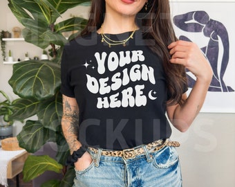 May include: A black t-shirt with the text "YOUR DESIGN HERE" in white, featuring a retro font style. The shirt is being worn by a person with a leopard print belt.