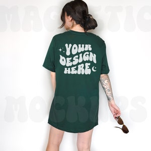 May include: A dark green t-shirt with short sleeves and a white graphic on the back that says "YOUR DESIGN HERE" with stars and a crescent moon.