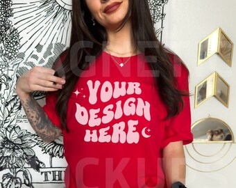 May include: A red t-shirt with a pink graphic that says "YOUR DESIGN HERE" with stars and a crescent moon on either side of the text.