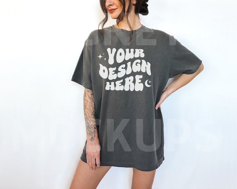 May include: A dark gray oversized t-shirt with the text "YOUR DESIGN HERE" in white. The shirt has a relaxed fit and a crew neck.