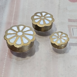 Könnte beinhalten: Drei Messing-Schmuckkästchen mit weißen Perlmutteinlagen in Form einer Blume. Die Kästchen sind in verschiedenen Größen.