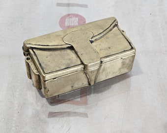 May include: A small, rectangular, brass box with a hinged lid. The box has a decorative design on the front and a clasp.
