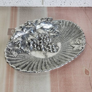 Peut inclure: Un plat de service en métal argenté en forme de panier tressé avec un motif de vigne. Le plat présente un groupe de raisins et de feuilles sculptés en relief.
