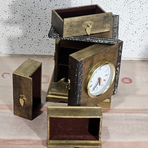 May include: A wooden box with a clock face and multiple compartments. The box is made of dark wood with gold accents and has a velvet lining. The clock face is white with black hands and numbers.